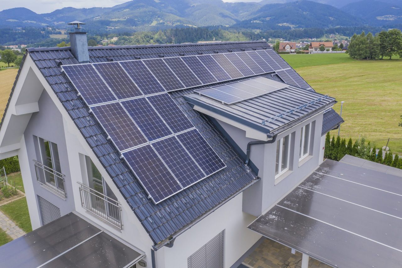 A high angle shot of a private house situated in a valley with solar panels on the roof