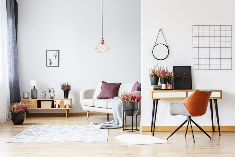 Round plate on the wall and designer chair at desk with heathers in bright living room interior with workspace 