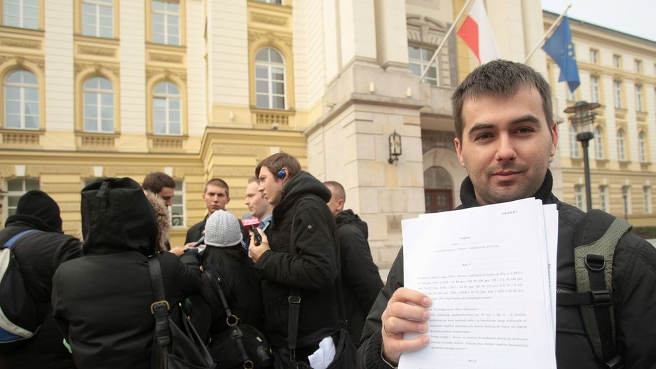 2009 r., pod KPRM. Błażej Spychalski pokazuje projekt zmiany ustawy o szkolnictwie wyższym podczas briefingu "Komitetu przywracamy ulgi dla studentów i uczniów" pt. "Stop płatnym studiom"