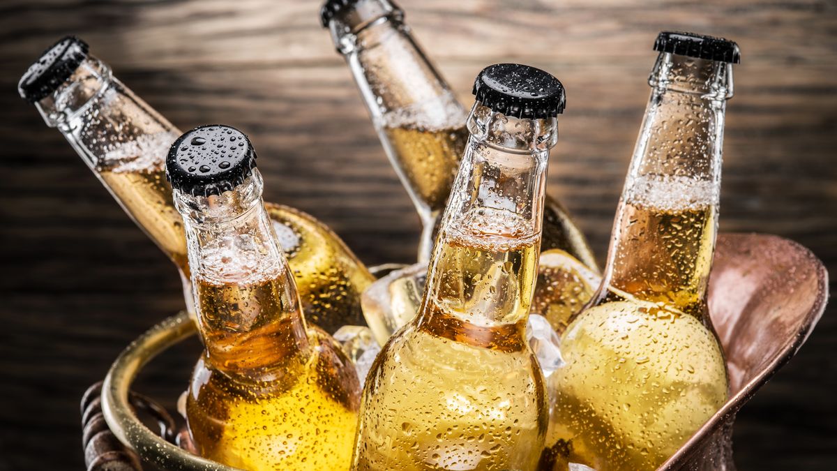 Cold bottles of beer in the brazen bucket on the wooden table.