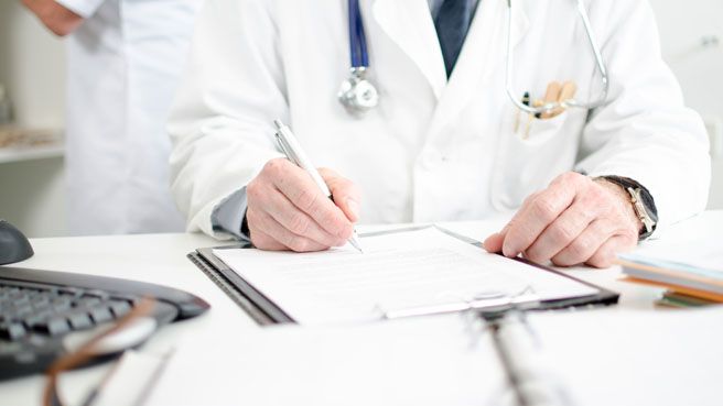 Doctor signing a medical report in his office