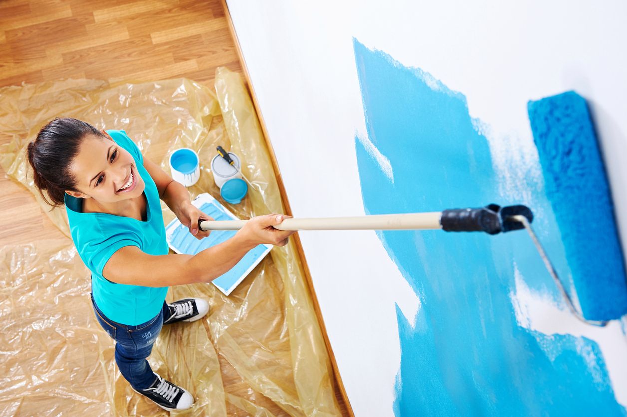 overhead view of woman painging new apartment standing on wooden floor 