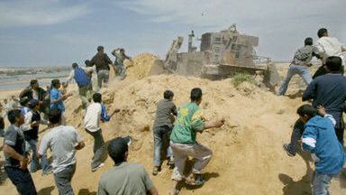 Palestyńczycy rzucają kamieniami w izraelski buldożer