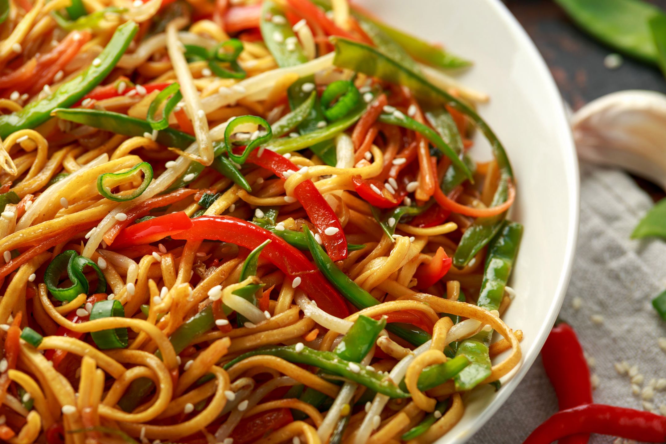 Chow mein, noodles and vegetables dish with wooden chopsticks. 
