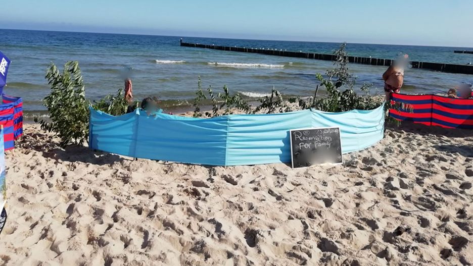 Gałęzie i konary z wydm, a obok tabliczka z informacją o "rezerwacji" na plaży w Ustroniu Morskim
