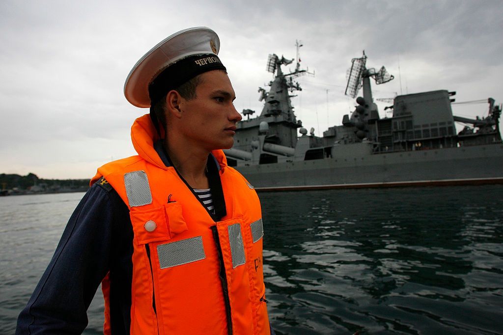 Rosyjski marynarz. W tle krążownik "Moskwa" 