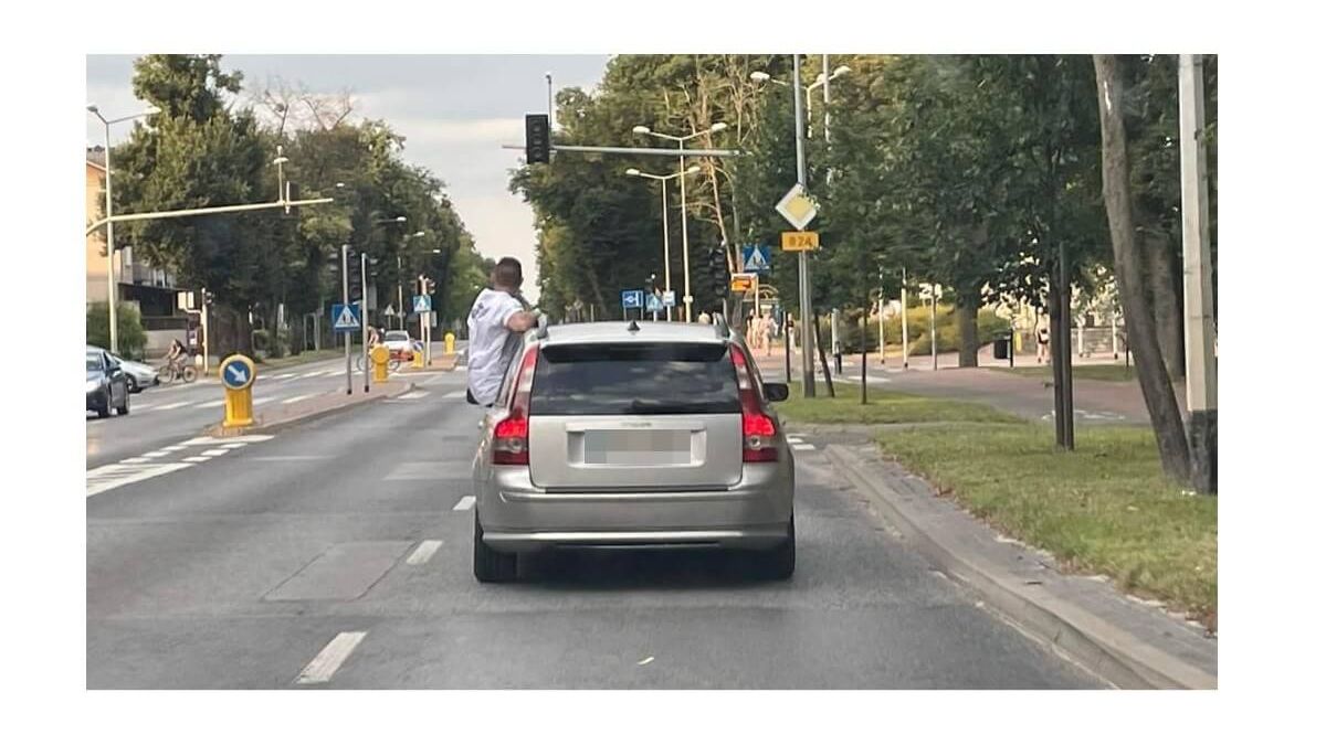 Kierowca siedzi na drzwiach samochodu w czasie jazdy