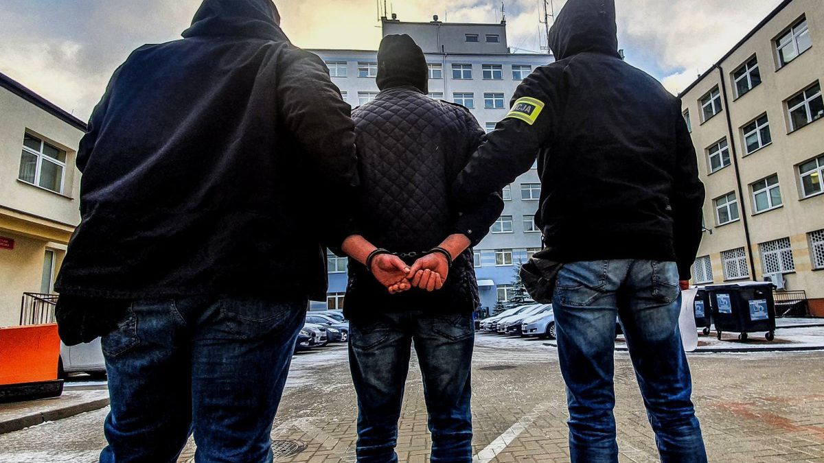 Na zdjęciu funkcjonariusze prowadzący mężczyznę skutego kajdankami