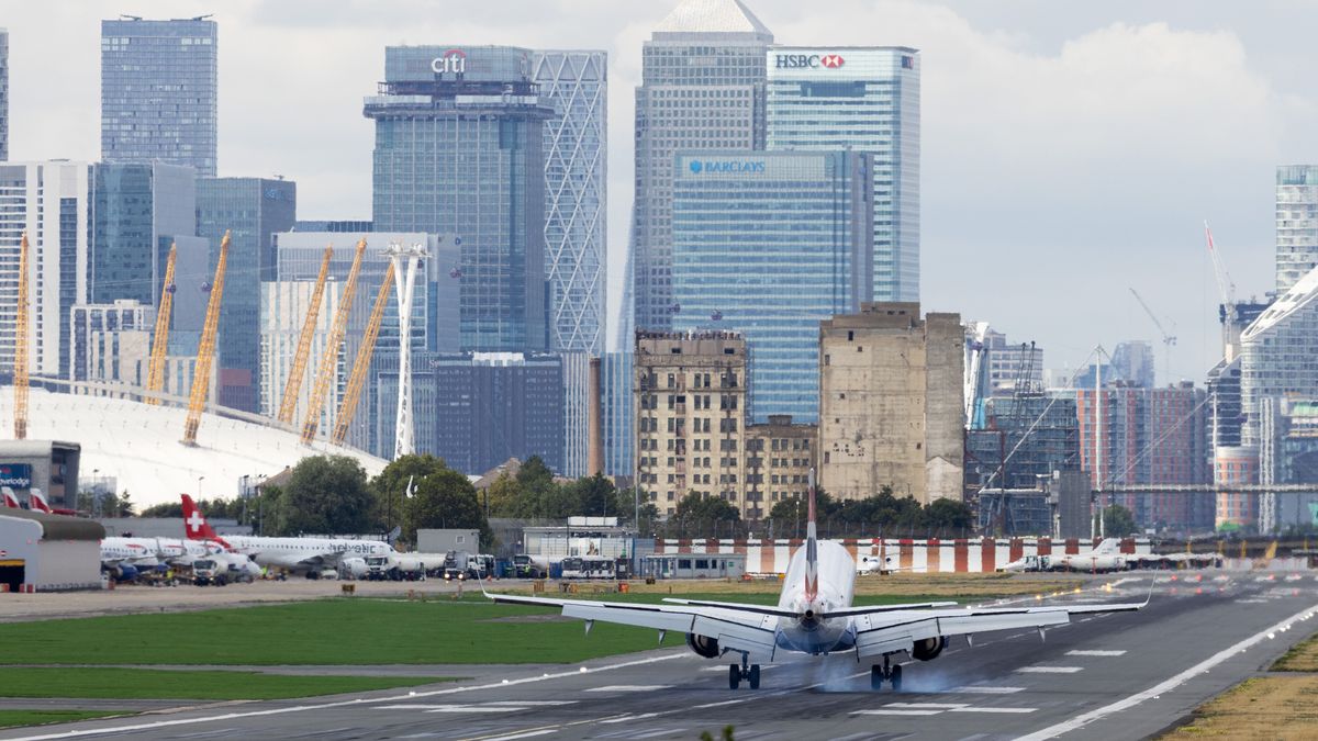 A passenger aircraft, operated by British Airways, lands at London City Airport Ltd. in view of the Canary Wharf business, financial and shopping district, in London, UK, on Thursday, Aug. 14, 2025. Macquarie Asset Management, via Macquarie European Infrastructure Fund 7, is set to buy a 25% stake in London City Airport. Photographer: Chris Ratcliffe/Bloomberg via Getty Images