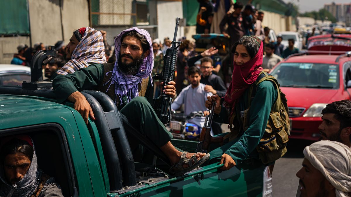 KABUL, AFGHANISTAN -- AUGUST 19, 2021: Afghans march down the street carrying banners and the flag of the Islamic Republic of Afghanistan, despite the presence of Taliban fighters around them, in Kabul, Afghanistan, Thursday, Aug. 19, 2021. About 200 people rallied towards the city center chanting ÒDeath to Pakistan, God Bless Afghanistan, Long Live the National Flag of Afghanistan.Ó \ (MARCUS YAM / LOS ANGELES TIMES)
