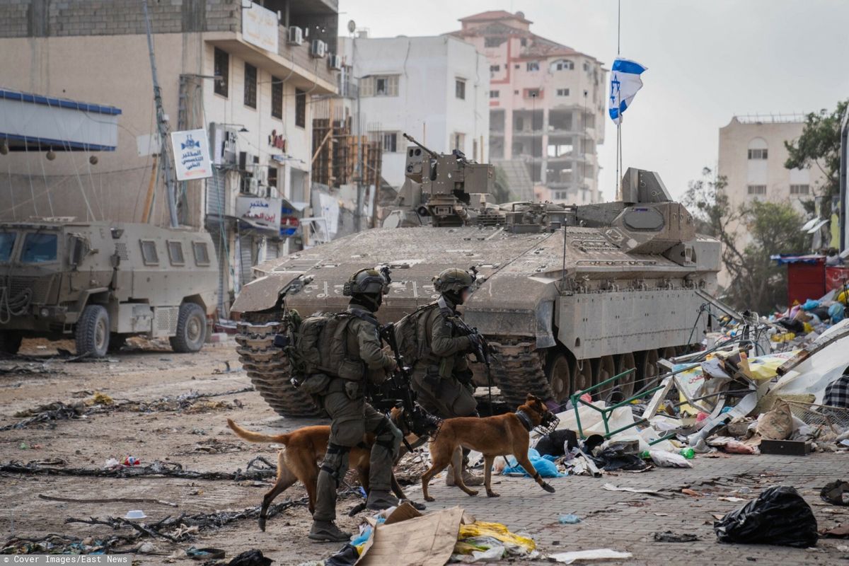 Izraelscy żołnierze z psami w Gazie. W tle transporter opancerzony