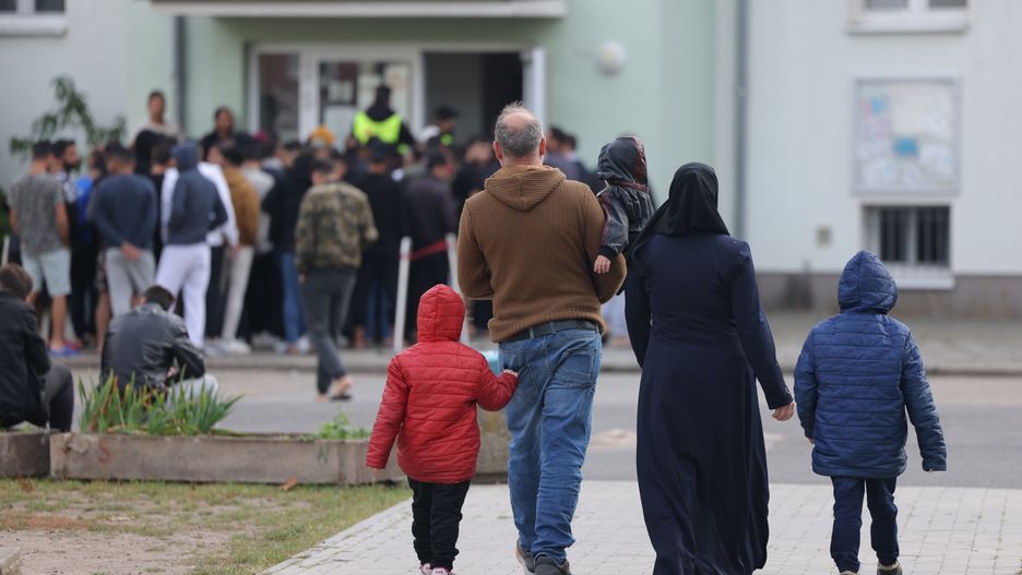 EISENHUETTENSTADT, GERMANY - OCTOBER 05: People queue for lunch at the initial reception facility for migrants and refugees on October 05, 2023 in Eisenhuettenstadt, Germany. The Eisenhuettenstadt facility serves as both a registration center and a temporary shelter for newly-arrived asylum seekers in the eastern state of Brandenburg. Germany is struggling to cope with a current large influx of migrants, mainly from Syria, Afghanistan and Turkey, arriving via Poland and the Czech Republic. (Photo by Sean Gallup/Getty Images)
