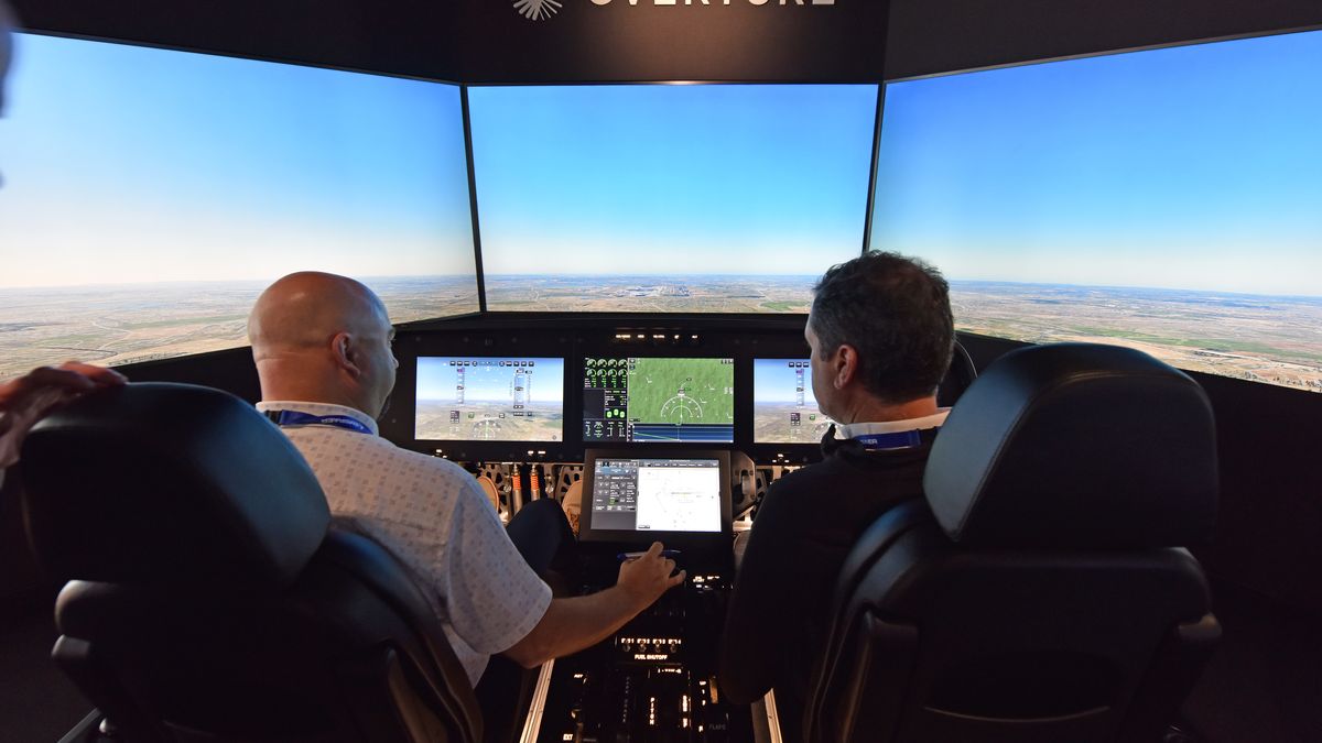 FARNBOROUGH, ENGLAND - JULY 23: Guests try out a flight simulator for the Overture Supersonic Airliner at the Boom Supersonic exhibition hall during the Farnborough International Airshow 2024 at Farnborough International Exhibition and Conference Centre on July 23, 2024 in Farnborough, England. Boom Supersonic Overture will be the World’s Fastest Airliner, Optimized for Speed, Safety, and Sustainability by using 100% sustainable aviation fuels (SAF). Boom's order book stands at 130 aircraft, including orders and pre-orders from American Airlines, United Airlines, and Japan Airlines. Farnborough International Airshow 2024 is host to leading innovators from the aerospace, aviation and defence industries. (Photo by John Keeble/Getty Images)