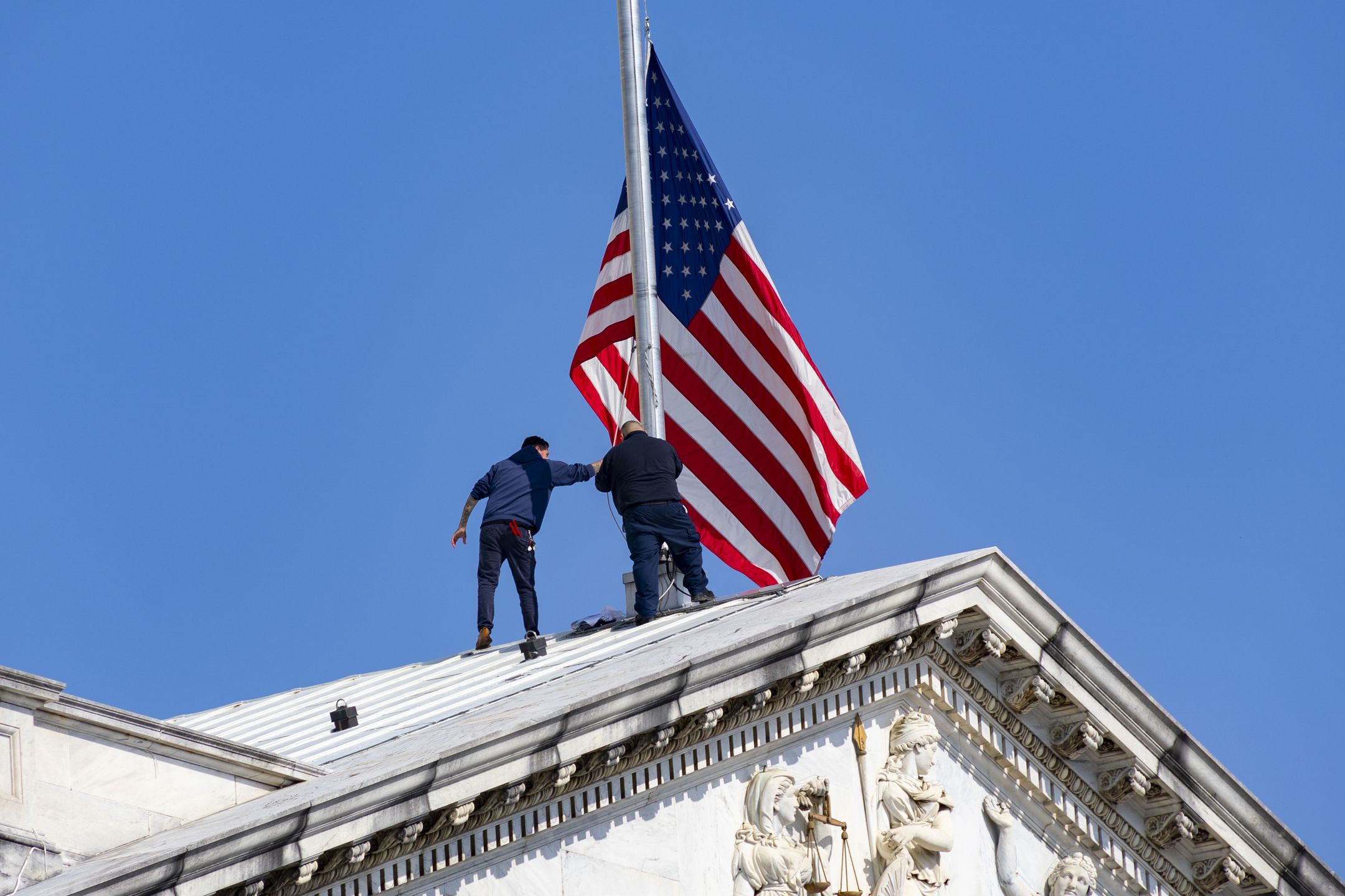 Workers adjusting the flag on the Capitol building. The United States Capitol under a clear blue sky, with American flag waving. Located on Capitol Hill at the eastern end of the National Mall in Washington, D.C., this iconic building is the seat of the U.S. Congress, the legislative branch of the federal government. The Capitol features a dome above its rotunda, designed by Thomas U. Walter and constructed between 1855 and 1866. The Statue of Freedom, a bronze statue, has crowned the dome since 1863. Washington, D.C., USA on May 8. 2023 (Photo by Nicolas Economou/NurPhoto via Getty Images)
