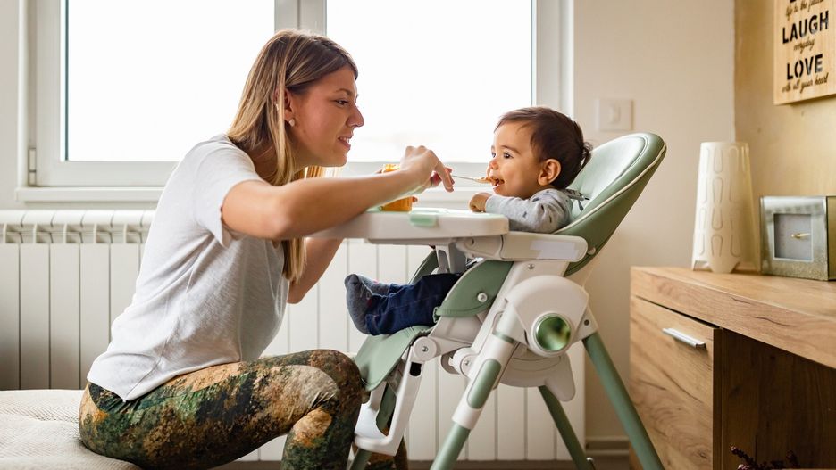 Family life. Mother feeding her baby at home.