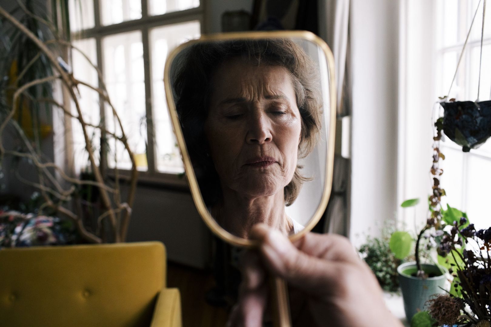 Reflection of upset senior woman on hand mirror at home
Maskot