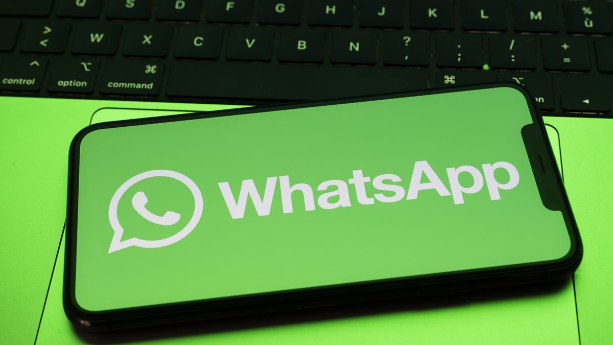 In Créteil, France, on September 29, 2025, the WhatsApp logo appears on a smartphone placed on a laptop keyboard, which reflects a green light. Meta, the parent company of WhatsApp and Meta AI, makes the Artificial Intelligence assistant mandatory in its instant messaging app. (Photo Illustration by Samuel Boivin/NurPhoto via Getty Images)