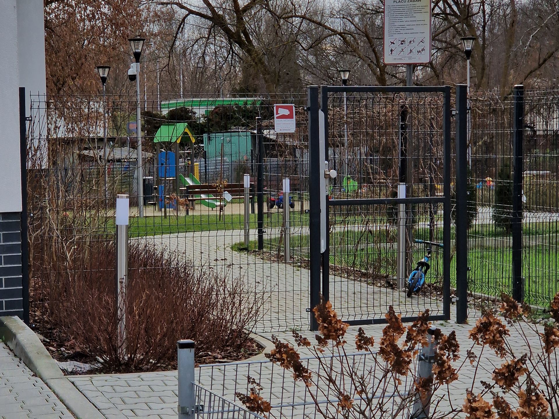 Na zdjęciu ogrodzenie blokujące dostęp na podwórko i plac zabaw