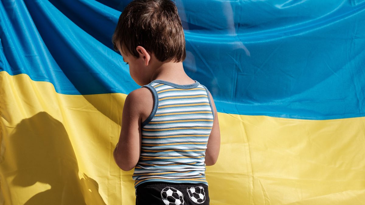 LVIV, UKRAINE - JUNE 26: Boy stands next to Ukrainian flag on Rynok (Market) Square in front of the Lviv City Hall on June 26, 2024 in Lviv, Ukraine. On June 26 Crimean Tatars mark the Day of National Flag, the yellow Taraq Tamga emblem on a blue background. (Photo by Les Kasyanov/Global Images Ukraine via Getty Images)