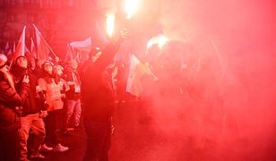 Zamaskowane osoby na Marszu Niepodległości. Słychać wybuchy, widać race