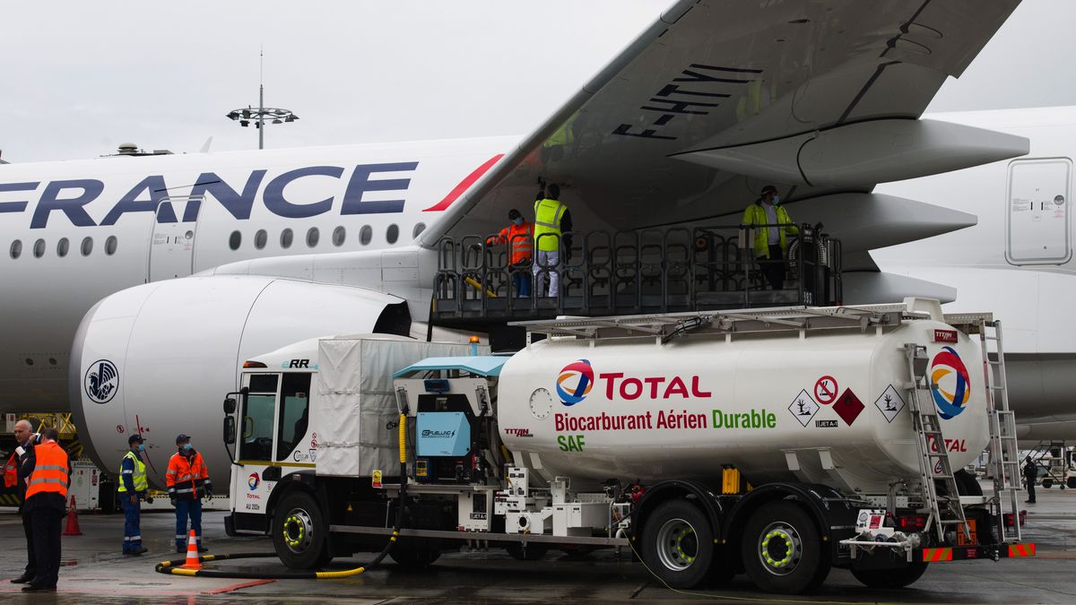 Workers connect a Total SE tanker truck to an Airbus A350 passenger plane, operated by Air France-KLM, during fueling with sustainable aviation fuel (SAF) ahead of a long-haul flight to Montreal, Canada, at Charles de Gaulle airport in Roissy, France, on Tuesday, May 18, 2021. Airbus SE will buttress its moonshot plan to build a hydrogen aircraft by the middle of the next decade with an effort to power conventional jets with sustainable fuels. Photographer: Nathan Laine/Bloomberg via Getty Images