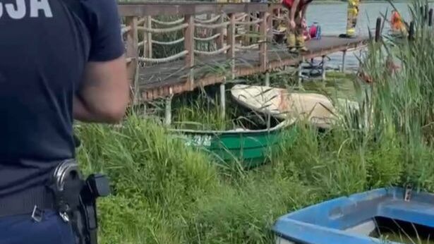 Policjant obserwujący akcję ratunkową na pomoście, gdzie strażacy przygotowują sprzęt nad wodą.
