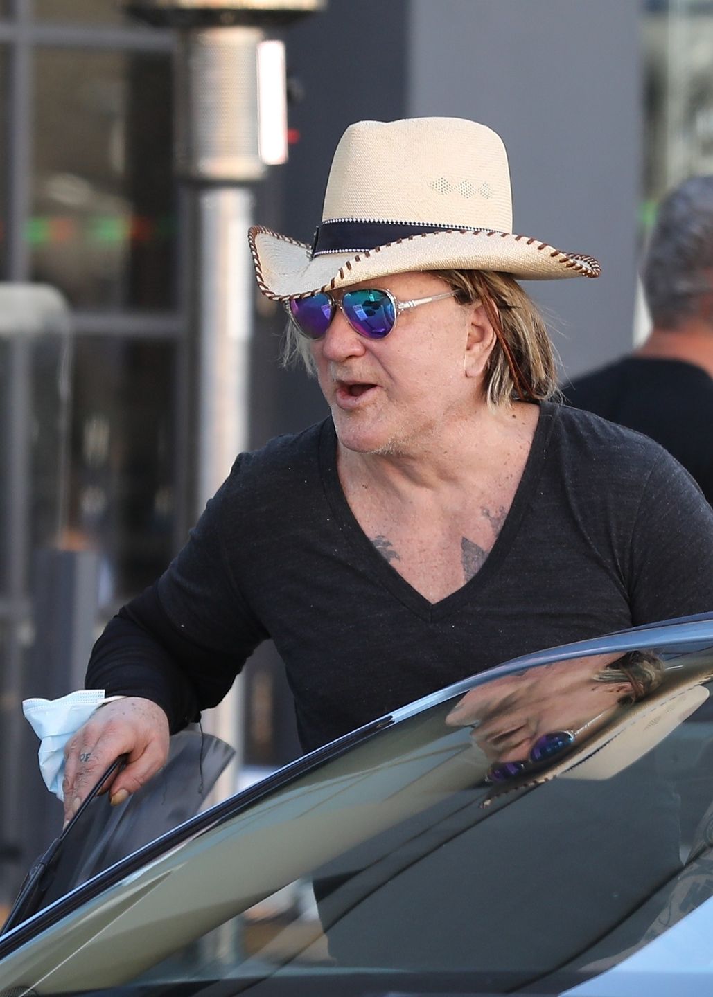 Zmarnowany Mickey Rourke wyłania się z samochodu w kowbojskim kapeluszu 