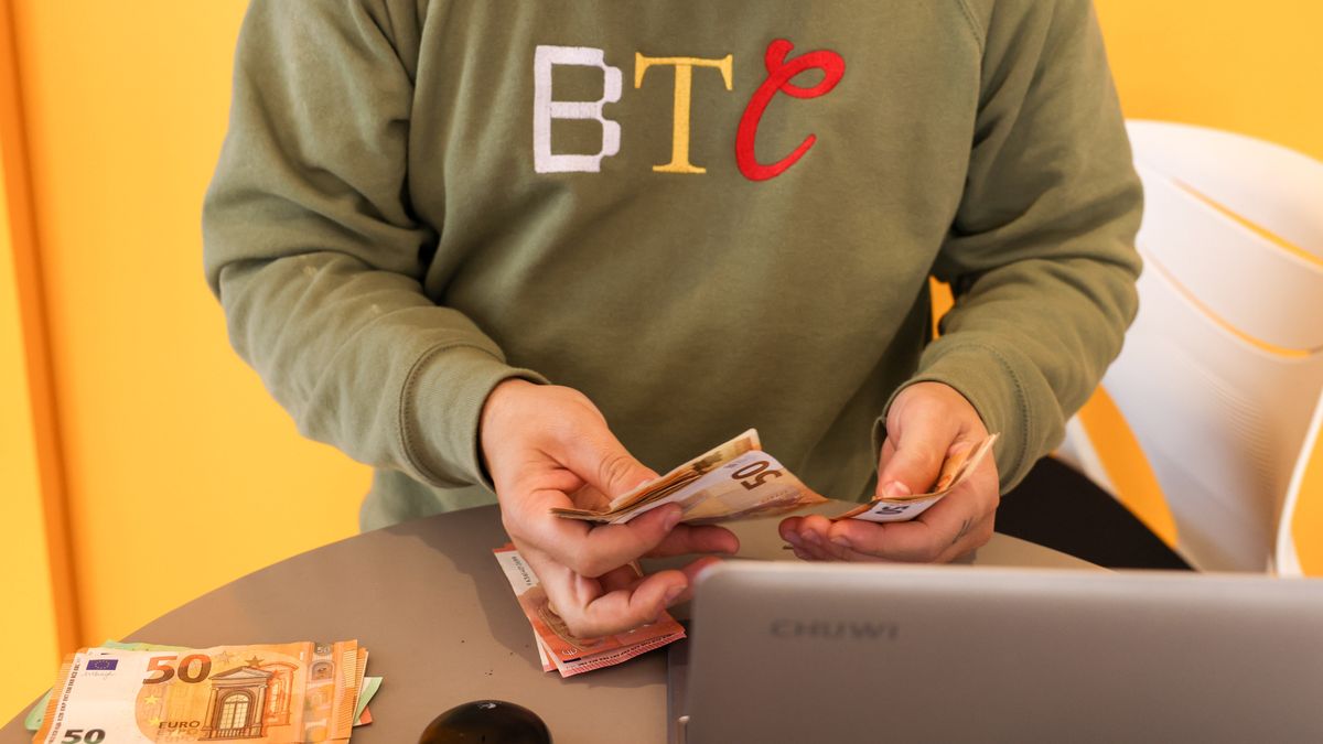 A worker with a BTC branded sweatshirt counts euro banknotes inside a BitBase cryptocurrency exchange in Barcelona, Spain, on Tuesday, Dec. 5, 2023. Bitcoin shrugged off a slide in global markets during a rally to a more than 19-month high, a sign of its decoupling from other assets. Photographer: Angel Garcia/Bloomberg via Getty Images