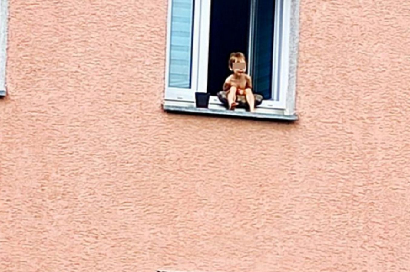 3-latka siedziała na parapecie otwartego okna.