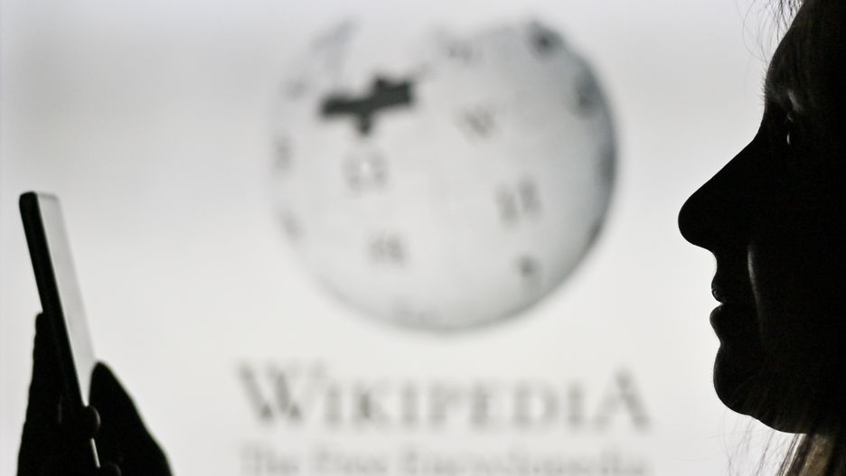 An image of a woman holding a cell phone in front of the Wikipedia logo displayed on a computer screen.
On Tuesday, January 12, 2021, in Edmonton, Alberta, Canada. (Photo by Artur Widak/NurPhoto via Getty Images)
