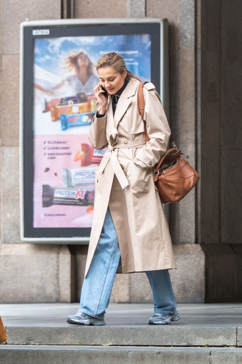 Małgorzata Socha maszeruje po deszczowej Warszawie ze smartfonem przy uchu