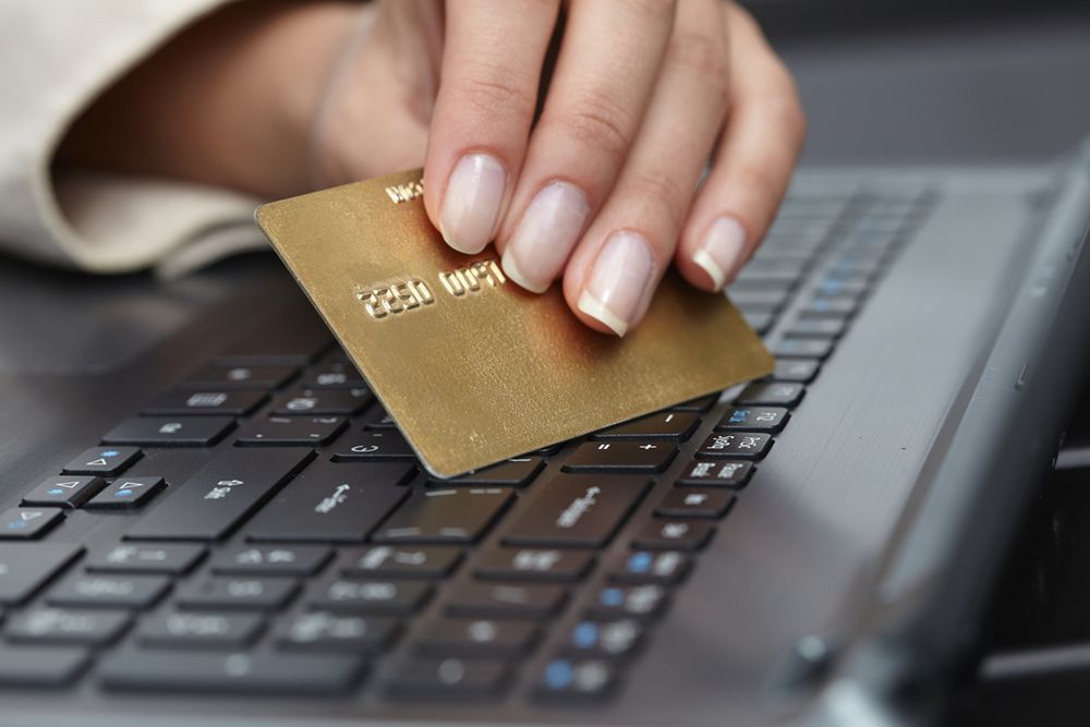 Zdjęcie Woman holding credit card on laptop pochodzi z serwisu Shutterstock