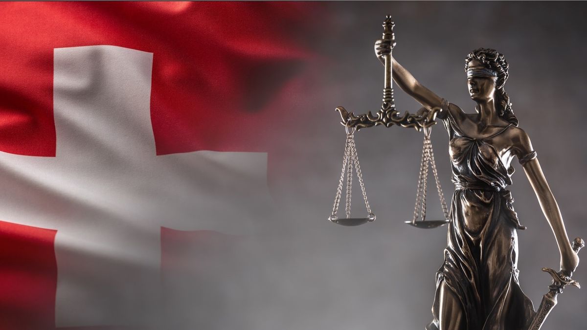 Na zdjęciu z lewej strony szwajcarska flaga a z prawej - Temida