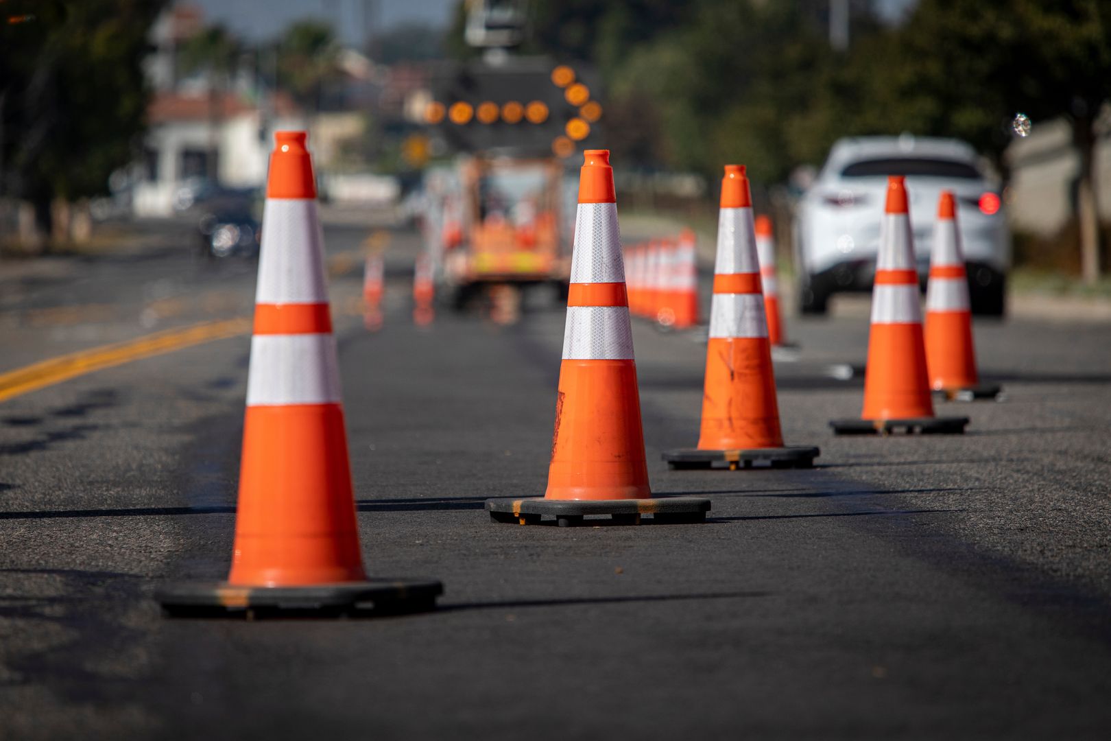 Traffic cones on road with electronic arrow pointing to the right to divert traffic and white car in distanceFRANK ARMSTRONGarrow, beware, equipment, prohibit, hazard, delay, driving, protection, notice, symbol, repair, barricades, pylons, post, signage, highway, travel, attention, closed, work, city, urban, danger, sign, transportation, street, traffic control, safety, control, right, construction site, construction, roadwork, asphalt, car, caution, cones, divert, infrastructure, line, maintenance, orange, orange cones, organized, pointing, road, row, traffic, traffic cones, warn