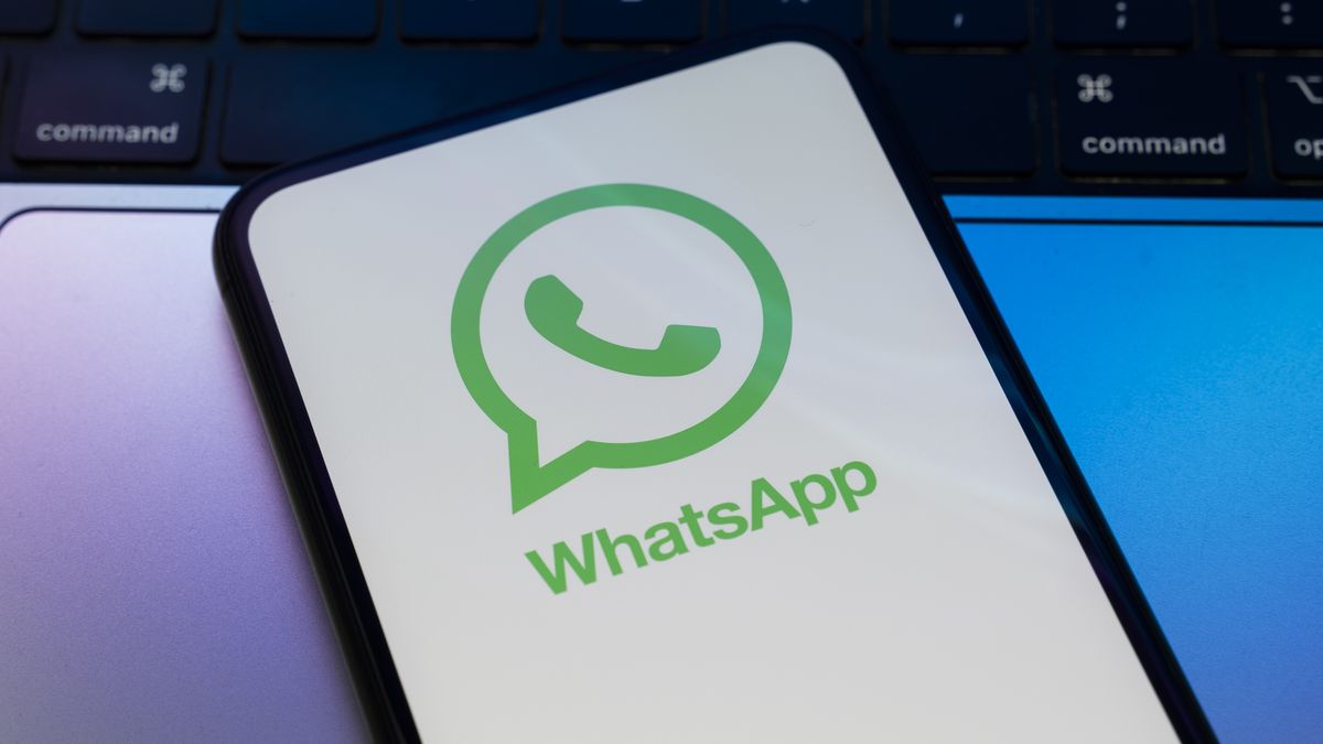 In Créteil, France, on September 29, 2025, the WhatsApp logo appears on a smartphone placed on a laptop keyboard, which reflects blue and purple light. Meta, the parent company of WhatsApp and Meta AI, makes the artificial intelligence assistant mandatory in its instant messaging app. (Photo Illustration by Samuel Boivin/NurPhoto via Getty Images)