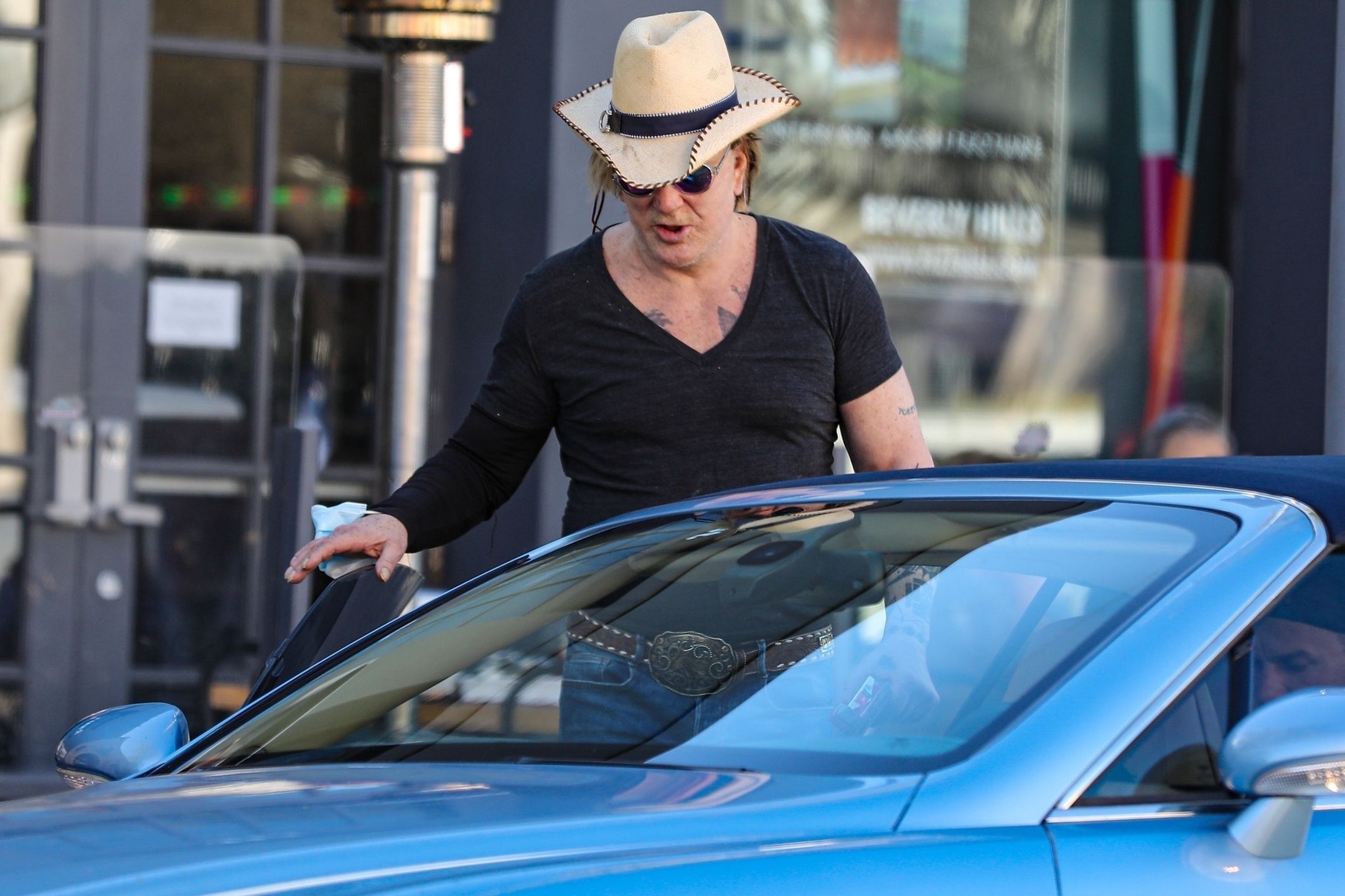 Zmarnowany Mickey Rourke wyłania się z samochodu w kowbojskim kapeluszu 