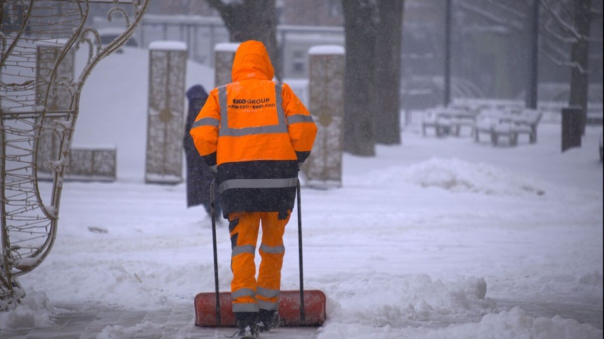 Mężczyzna odśnieżający chodnik pokryty śniegiem