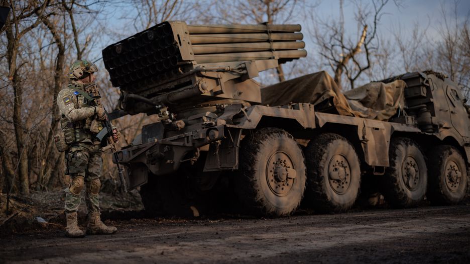 DONETSK OLBAST, UKRAINE - MARCH 7: Ukrainian soldier with assault rifle stands near RM-70 Vampire multiple rocket launcher on March 7, 2023 in Donetsk Oblast, Ukraine. On 24 February 2022, Russia invaded Ukraine in an escalation of the Russian-Ukrainian war that started in 2014. The full-scale invasion is the largest military attack in Europe since World War II. (Photo by Oleg Palchyk/Global Images Ukraine via Getty Images)