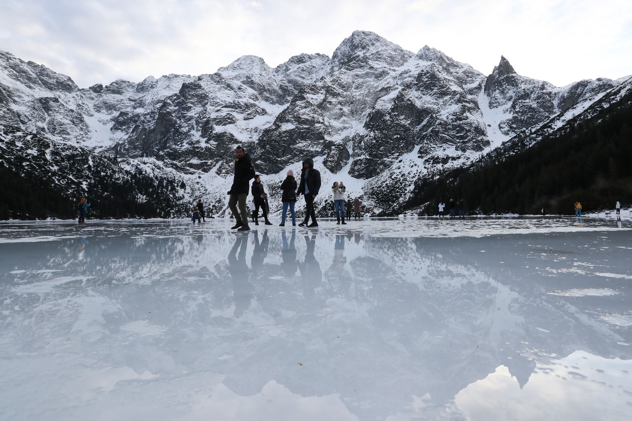 Tatry, Morskie Oko, 26.12.2022. Turyści na tafli lodu na jeziorze Morskie Oko w Tatrach, 26 bm. Tatrzański Park Narodowy ostrzega przed wchodzeniem na zamarznięte górskie jeziora � z powodu panujących w ciągu dnia dodatnich temperatur lód jest bardzo cienki i grozi załamaniem. (jm) PAP/Grzegorz Momot
