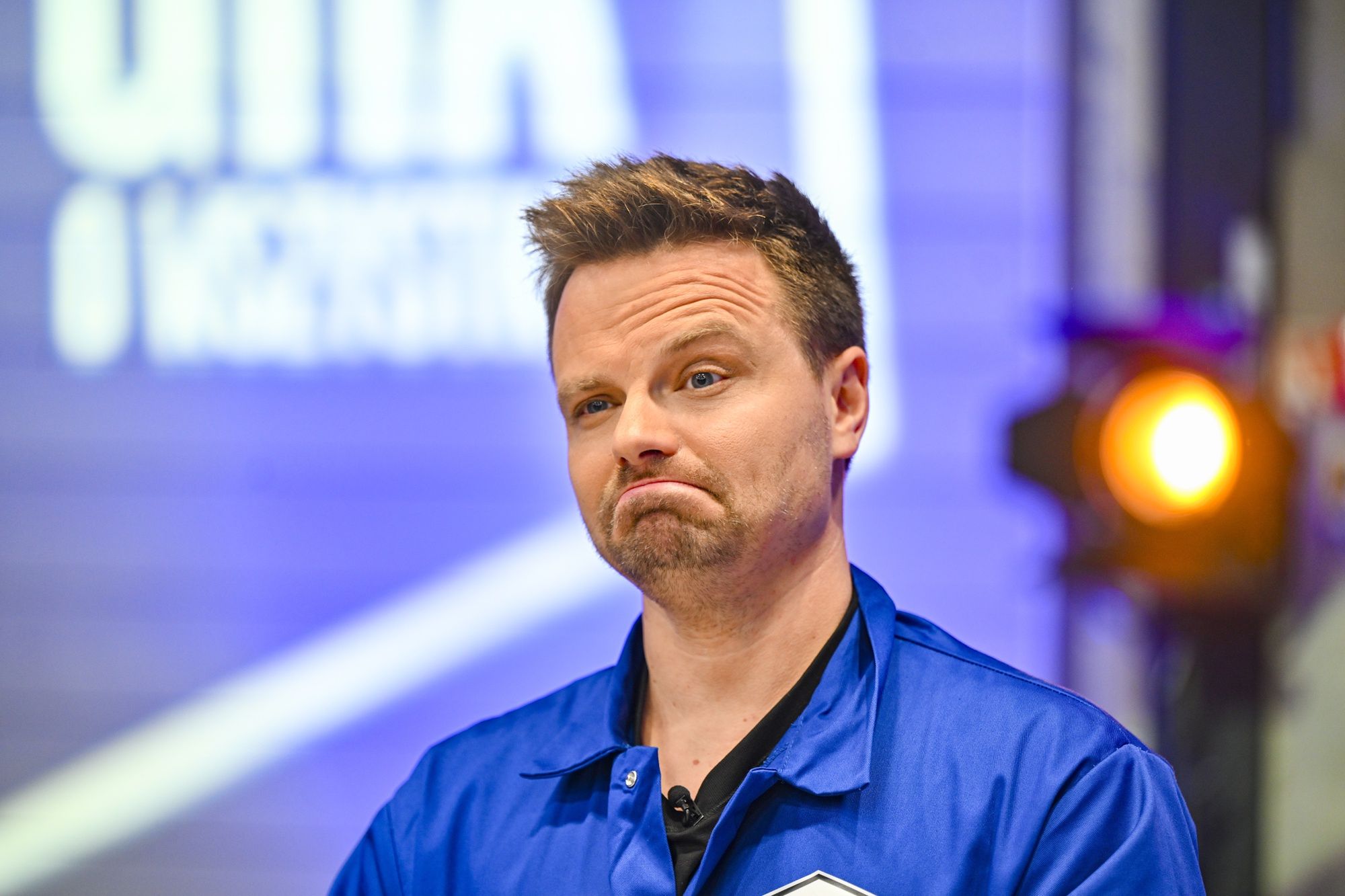 Na zdj.: Marcin Hakiel, Fot. AKPAluty 2026, 99 GRA O WSZYSTKO VIP, nagranie programu, niewielki zarost, pozowanie, spojrzenie w bok, Plan programu "99 GRA O WSZYSTKO VIP", bluza niebieska, październik 2025, plan, TVN, styl casual, Marcin Hakiel