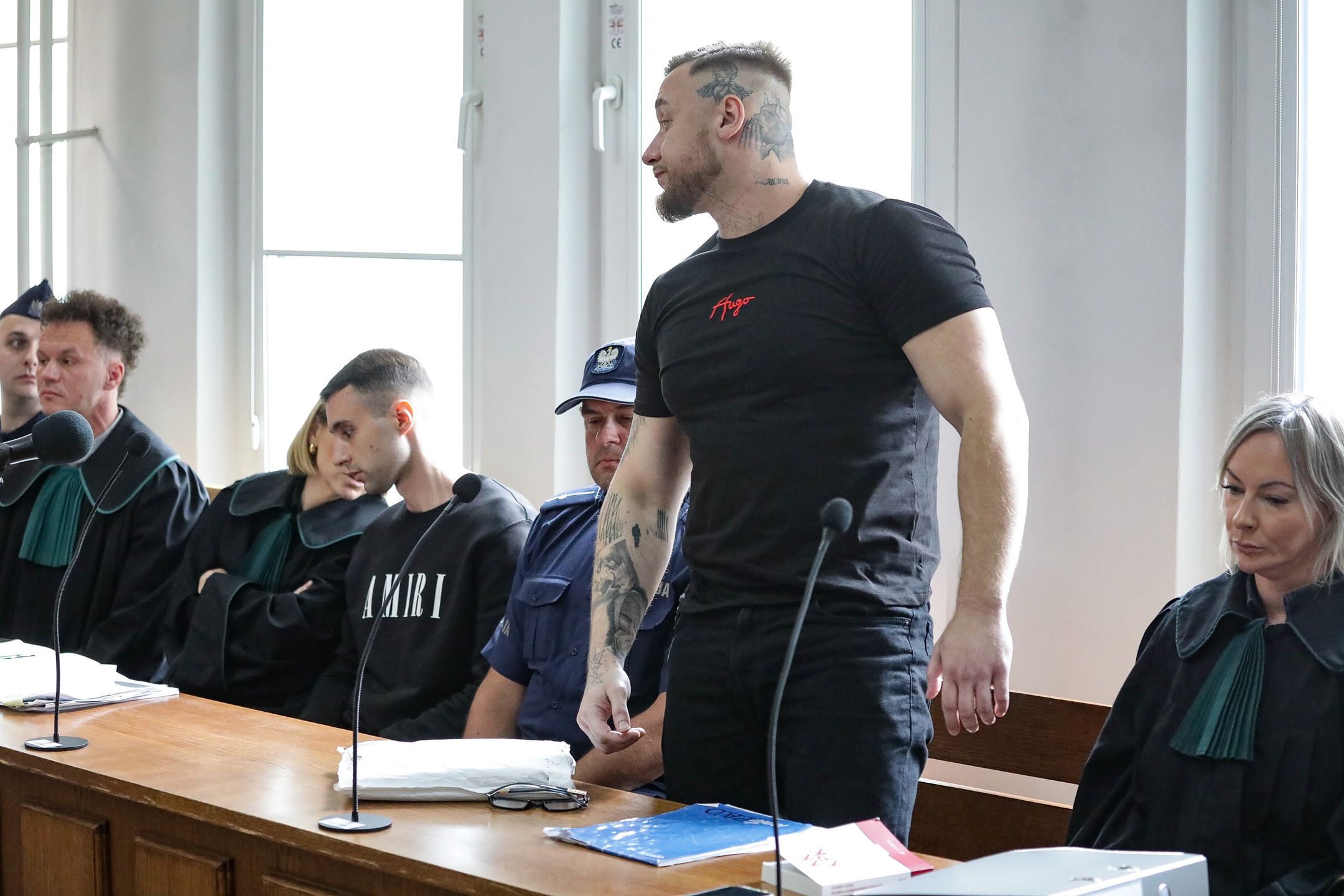 Warszawa, 17.06.2025. Oskarżeni Łukasz Żak (2P) i Maciej Osiński (4L) oraz obrońca, mec. Izabela Ławińska (P) na sali rozpraw Sądu Rejonowego dla Warszawy-Śródmieścia, 17 bm. Rozpoczął się proces Łukasza Żaka oskarżonego o spowodowanie śmiertelnego wypadku na Trasie Łazienkowskiej we wrześniu 2024 r. Uczestniczyli w nim kierujący volkswagenem arteonem Łukasz Żak, a także jadąca fordem focusem czteroosobowa rodzina. W wyniku zderzenia zginął 37-letni pasażer forda Rafał P. Do szpitala trafiły trzy osoby z tego auta: 37-letnia kierująca samochodem żona zmarłego mężczyzny i ich dzieci w wieku czterech i ośmiu lat, a także kobieta ? Paulina K., która podróżowała volkswagenem. Tuż przed wypadkiem auto Łukasza Żaka pędziło 226 km/h w terenie, gdzie dopuszczalna prędkość wynosi do 80 km/h; wg biegłych kierujący był pijany, a swoją jazdę nagrywał trzymanym w ręku telefonem komórkowym. W tej sprawie Prokuratura postawiła też zarzuty nieudzielenia pomocy i poplecznictwa 5 innym mężczyznom, a jednemu ? poplecznictwa. (jm) PAP/Tomasz Gzell *** UWAGA!!! SĄD ZGODZIŁ SIĘ NA PODAWANIE DANYCH I UTRWALANIE WIZERUNKU ŁUKASZA ŻAKA I PIĘCIU Z SZEŚCIU POZOSTAŁYCH OSKARŻONYCH! ***