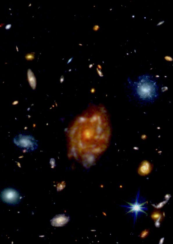 The "Big Wheel" galaxy is visible in the center. The bright blue galaxy (upper right corner) is only about 1.5 billion light-years away from us, which places the "Big Wheel" about 50 times farther away. Although both appear to be similar in size, the enormous distance of the "Big Wheel" reveals its truly colossal physical scale. (Webb Telescope)