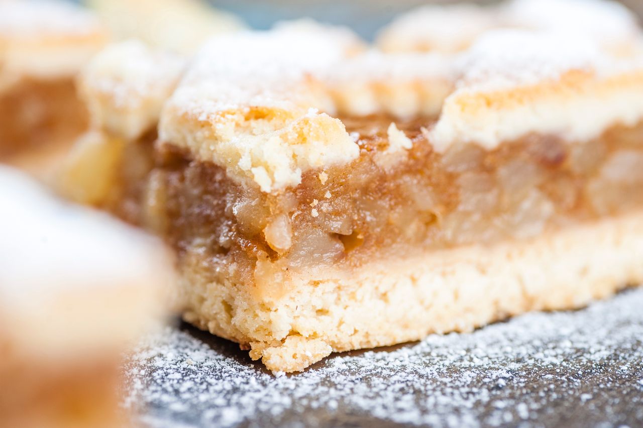 A piece of apple pie sprinkled with powdered sugar