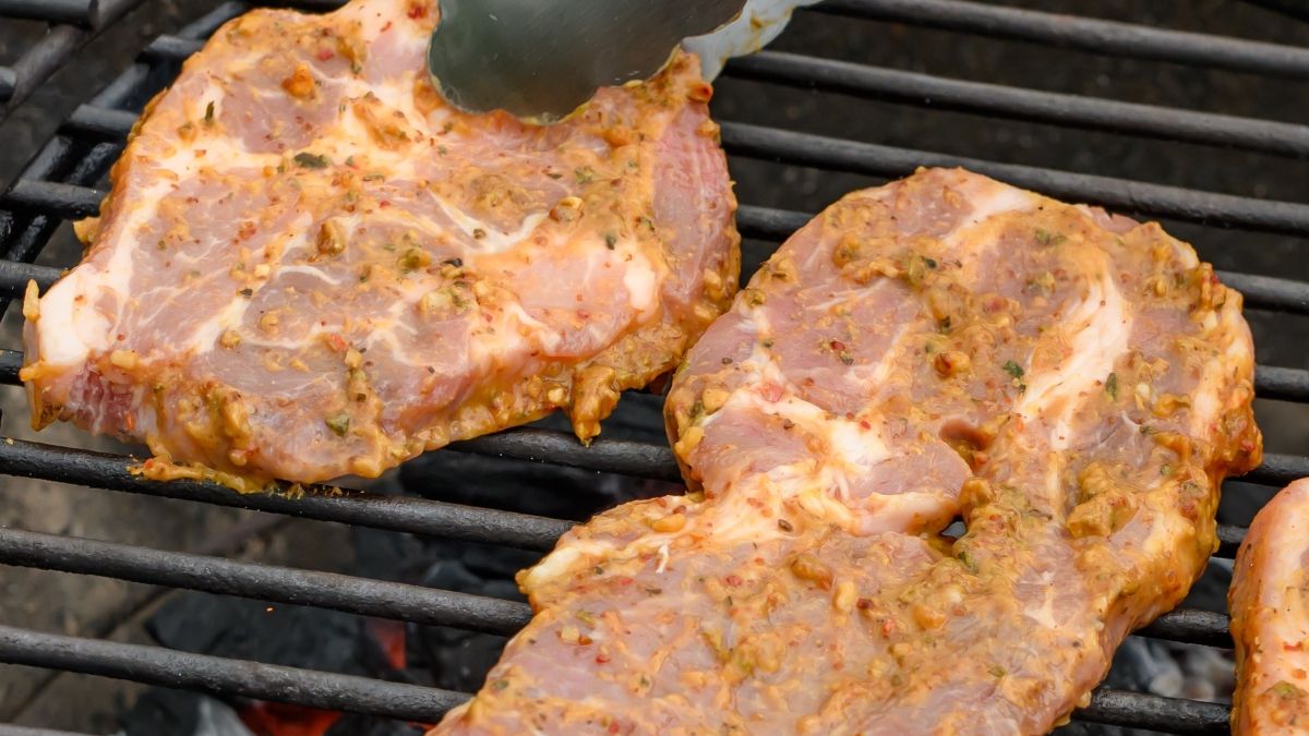 Karkówka w plastrach leżąca na ruszcie nad żarem