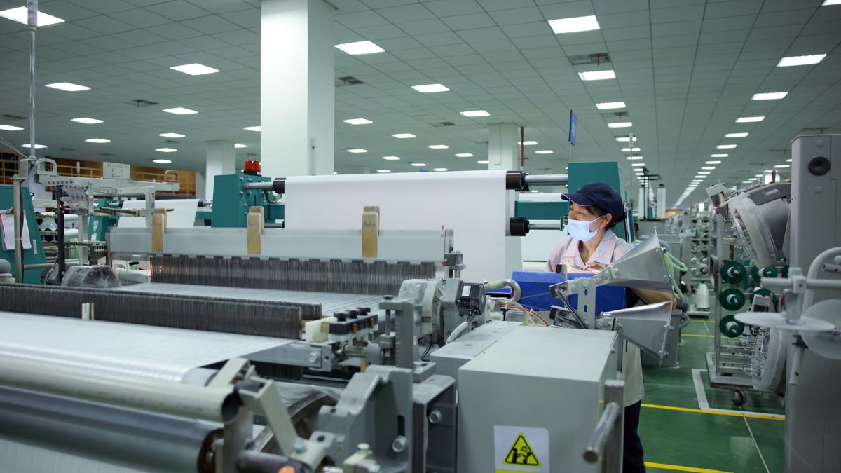 TONGXIANG, CHINA - APRIL 14: A worker operates machines to produce electronic glass fabric on April 14, 2026 in Tongxiang, Zhejiang Province of China. As the building materials industry accelerates its transition from traditional manufacturing to intelligent manufacturing, glass fiber has become a crucial component of technological upgrades, serving as a key material for wind power, new energy vehicles, and 5G communications. (Photo by Sun Yangyang/China News Service/VCG via Getty Images)