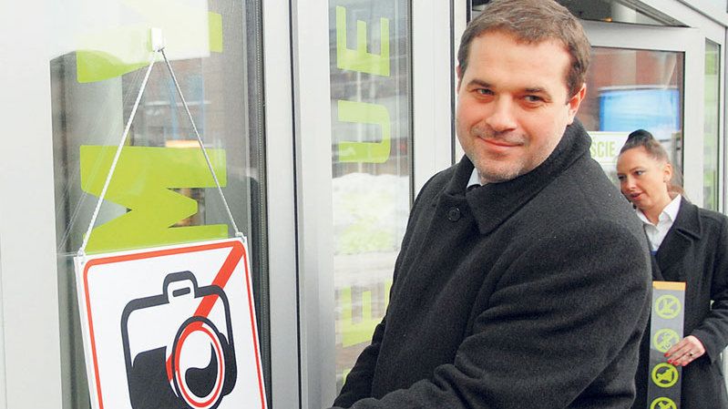 Sławomir Murawski, dyrektor Manufaktury, zamienia znak zakazu fotografowania na znak aparatu z uśmiechniętym obiektywem.