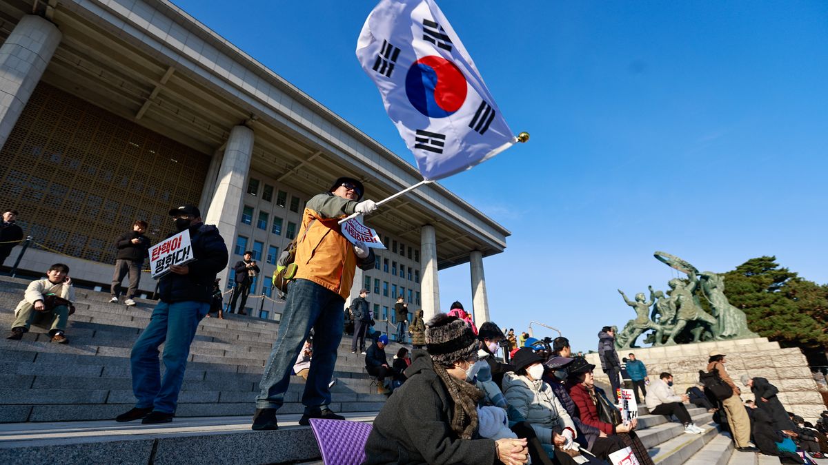 SEOUL, SOUTH KOREA - DECEMBER 04: Protesters demanding for the resignation of South Korean president Yoon Suk Yeol chant slogans outside the National Assembly Building, in Seoul, South Korea, on December 04, 2024. Yoon Suk Yeol declared in the late hours of December 03 an emergency martial law, which has sparked outrage among the public and promoted lawmakers to submit a motion to impeach the president. (Photo by Daniel Ceng/Anadolu via Getty Images)