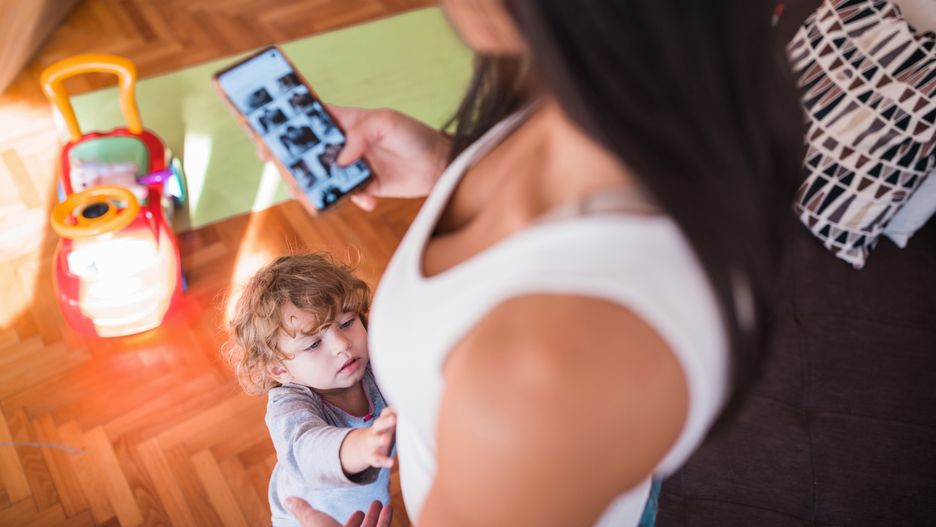 Toddler approaching woman looking at photo gallery on mobile phone
Mother using smart phone and toddler wanting to be held
Dobrila Vignjevic
