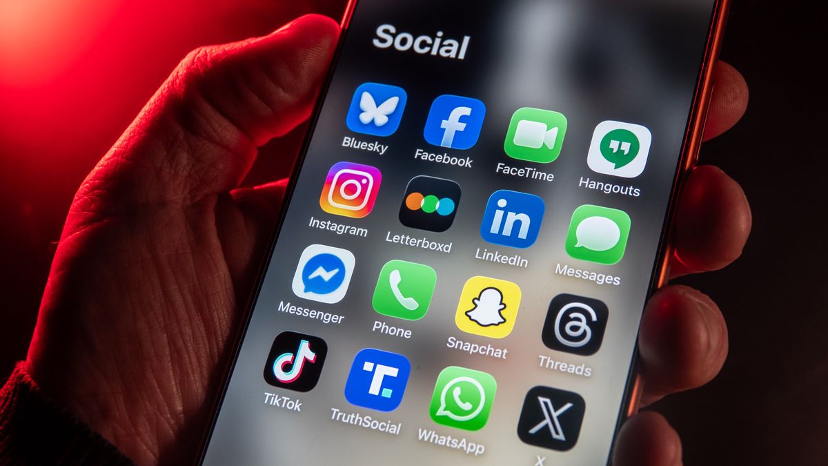 BATH, UNITED KINGDOM - JANUARY 25: In this photo illustration a man holds an iPhone screen displaying various social media and messaging apps on January 25, 2026 in Bath, England. In the picture is top row left to right, Bluesky, Facebook, FaceTime and Hangouts. On the Second row left to right is Instagram, Letterboxd, LinkedInand Messages. On the third row, left to right is Messenger, Phone, Snapchatand Threads. On the bottom row. left to right is TikTok, Truth Social, WhatsApp an X. In the UK, a ban on social media for under-16s has been backed by the House of Lords following the Australian law which aims to stop children under 16 from having social media accounts and social media platforms, including TikTok, Facebook, Snapchat, Reddit, X, formerly Twitter, and Instagram potentially being be fined for preventing children younger than 16 from having social media accounts. (Photo by Anna Barclay/Getty Images)