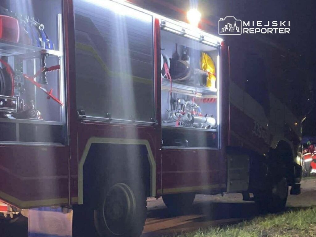 W nocy widać włączoną lampę w bagażniku wozu strażackiego, oświetlającą sprzęt gaśniczy.